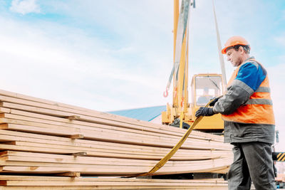 Low angle view of man standing on roof against sky