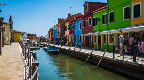 Boats in canal amidst buildings in city against sky