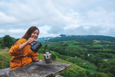 An asian woman making drip coffee with a beautiful green mountain and nature in background