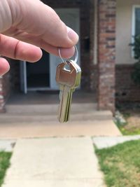 Cropped hand holding keys against house