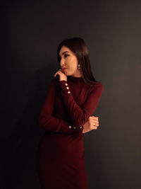 Young woman standing against black background