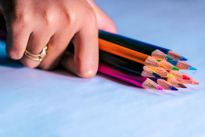 Close-up of human hand against colored pencils
