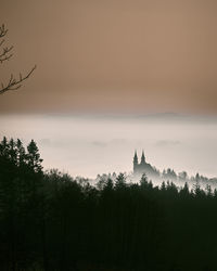 Silhouette of trees and building against sky during sunset