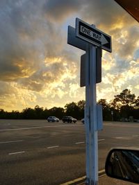 Cars on road against cloudy sky