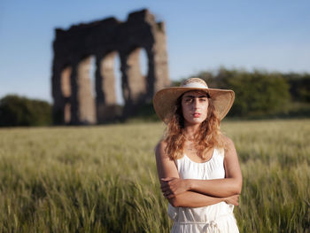 Portrait of young woman standing on field against sky