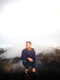 Young man on mountain against foggy weather