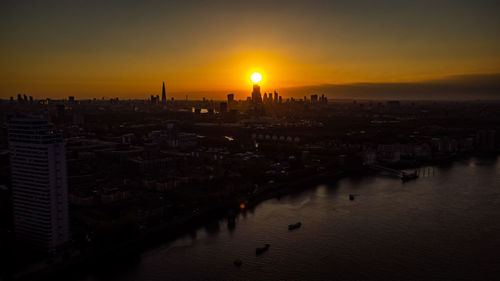 High angle view of river by buildings against sky during sunset