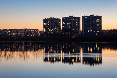 Reflection of illuminated buildings in lake at sunset