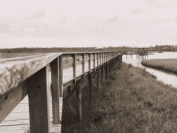 Wooden footbridge over river against sky
