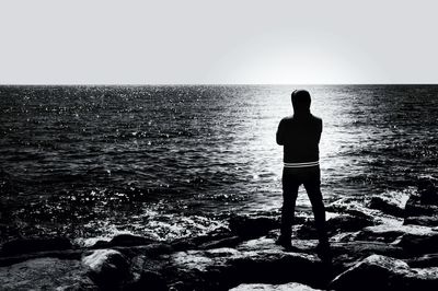 Man standing on rocks by sea