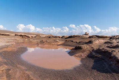 Gathered water in a arid lake in dasht e lut or sahara desert with cloudy sky