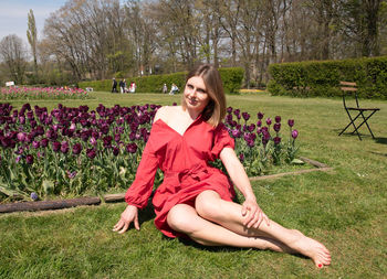 A young beautiful girl in a red dress in spring park plays with her hair,flirts