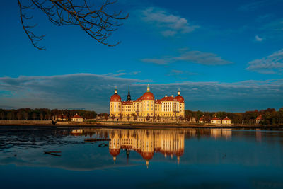 Reflection of building on water in city against sky