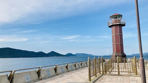 Lighthouse by sea against sky