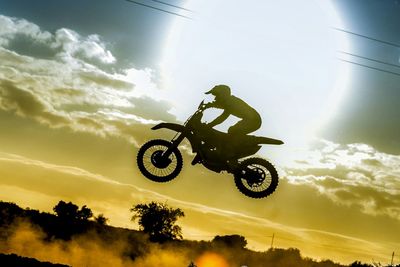 Low angle view of a man jumping on cloudy sky