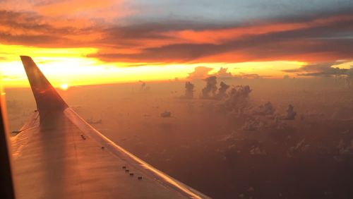 Airplane wing against sky during sunset