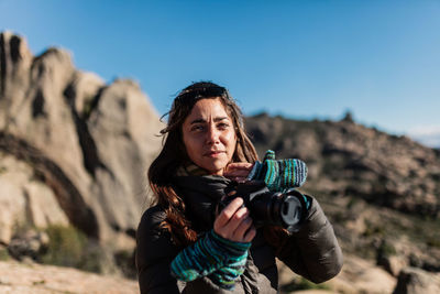 Portrait of woman photographing on rock