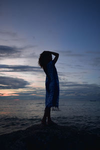 Full length of woman standing on beach against sky during sunset