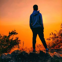 Rear view of man standing against orange sky