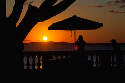 Silhouette people against sea during sunset
