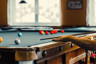 Cropped hand of man playing pool in room