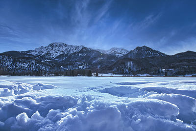 Scenic view of snow covered mountains against blue sky