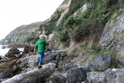 Small child walking on log near ocean in new zealand