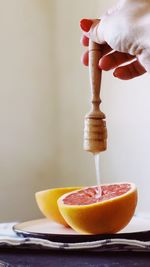 Cropped hand pouring honey on grapefruit