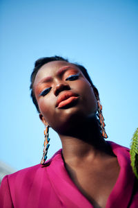 Low angle view of a fashionable black woman against clear blue sky