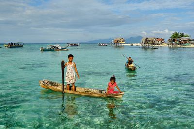 People on boat in sea against sky