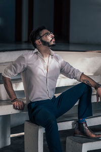 Young man looking away while sitting on seat