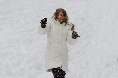 Portrait of smiling young woman standing in snow