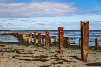 Iron posts on beach against sky