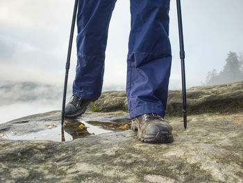 Low section of man standing on mountain against sky