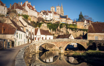 Bridge over canal amidst buildings in town against clear sky