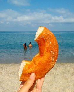 Close-up of hand holding ice cream in sea