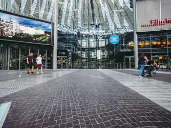 People walking on footpath amidst buildings in city