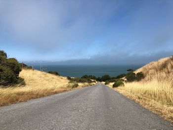 Road amidst land against sky