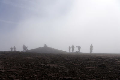 Silhouette people on barren land against sky