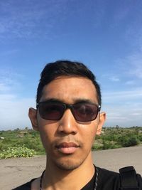 Portrait of young man wearing sunglasses against sky