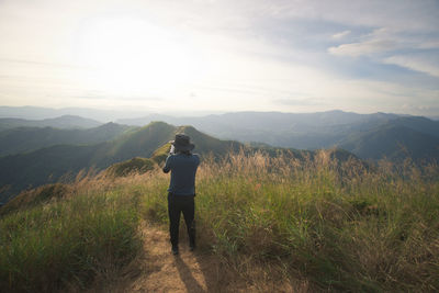 Rear view of man looking at mountains against sky