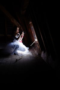 Young woman photographing through window in darkroom