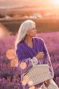 Woman holding basket standing in flower field