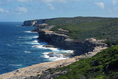 Scenic view of sea by cliff against sky