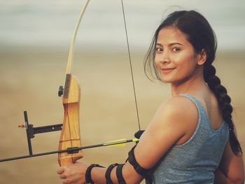 Close-up of woman aiming bow outdoors