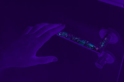 Close-up of hand holding illuminated light against blue background