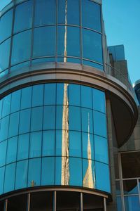 Low angle view of glass building against blue sky