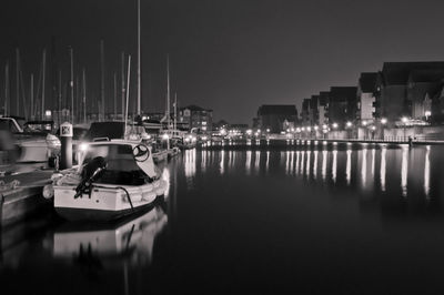 Boats moored at harbor against clear sky at night