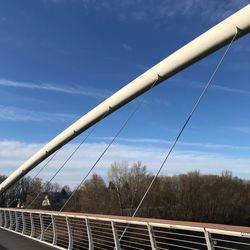 Low angle view of railing by trees against sky