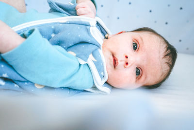 Portrait of cute baby lying down on bed at home